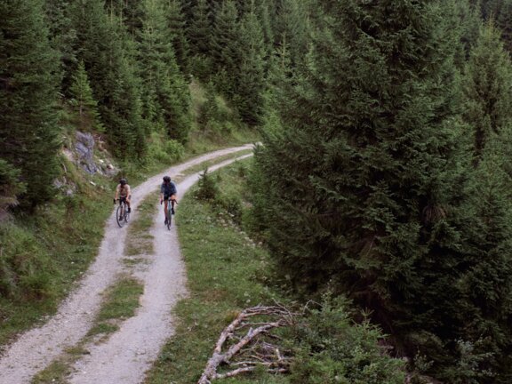 Zwei Mountainbiker auf einem Forst-Radweg im Wald im Tannheimer Tal Zwei Mountainbiker auf einem Forst-Radweg im Wald im Tannheimer Tal