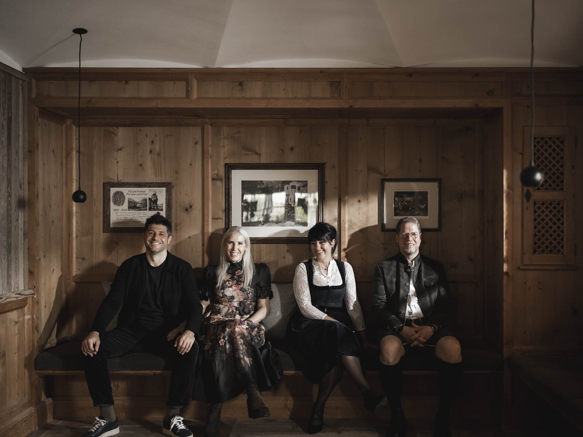 Familie Zimmermann und Familie Mattersberger sitzen in einer traditionellen Tiroler Stube im Wellnesshotel Der Engel