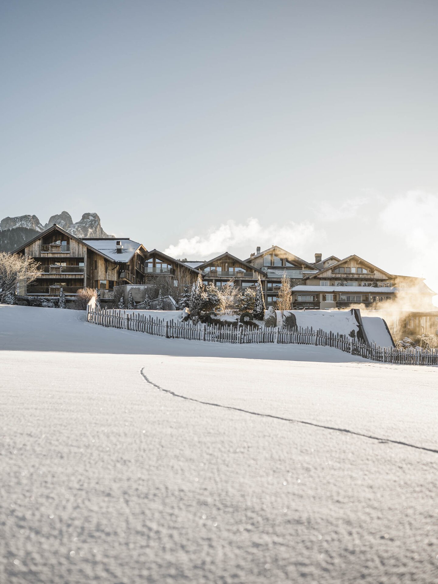 Außenaufnahme vom Hotel der Engel im Winter mit weißer Winterlandschaft im Vordergrund und den schneebedeckten Alpen im Hintergrund