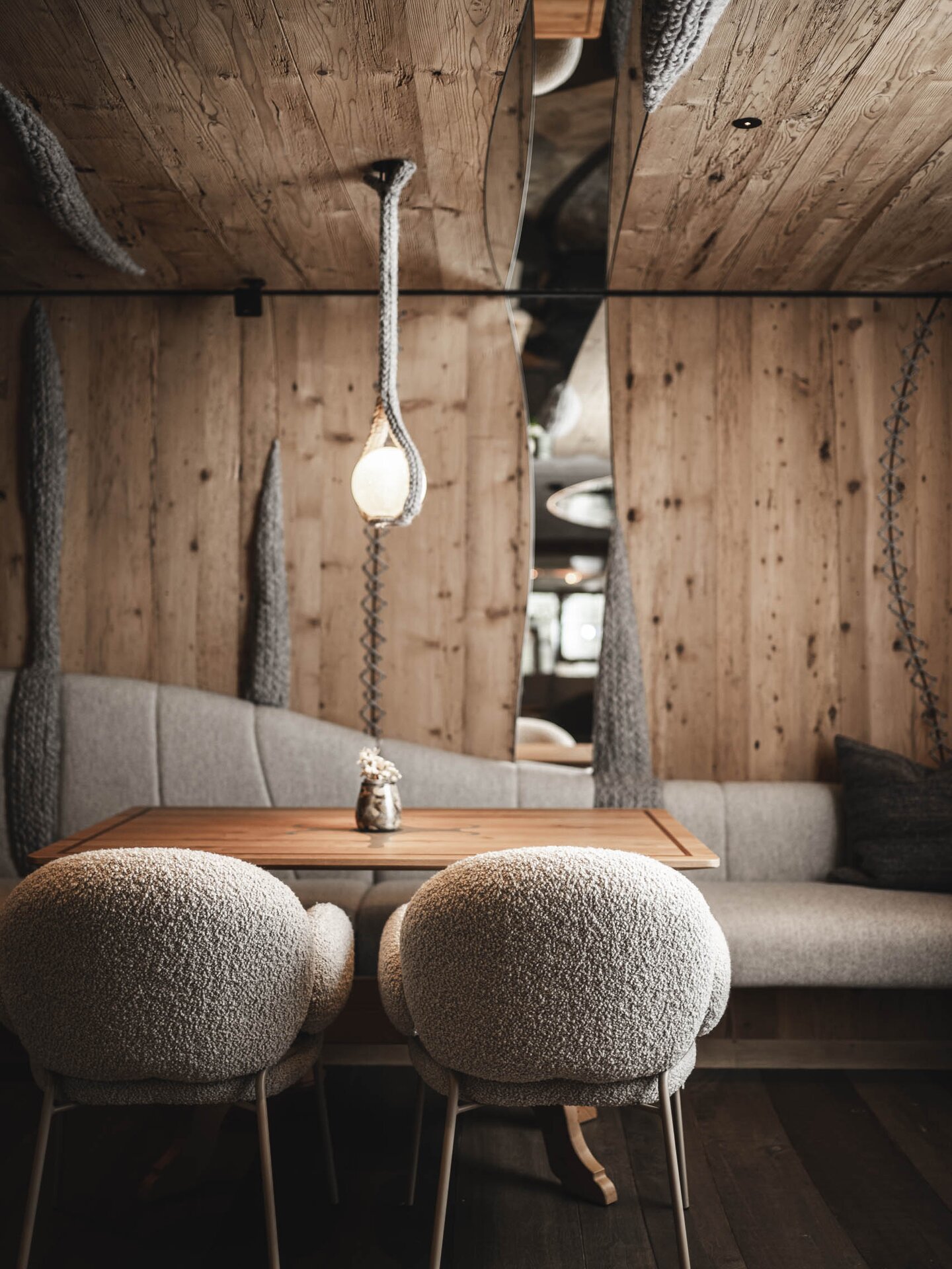 Designer-Sessel in der Bar 1748 von Freifrau und echter Holztisch vor Holzwand und gemütlicher Sitzbank