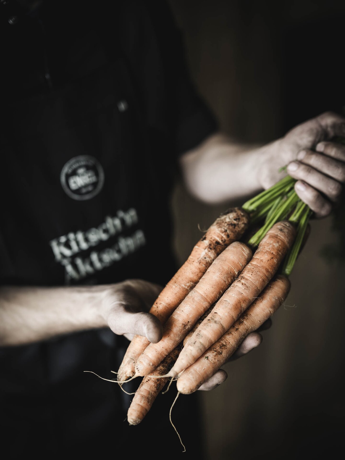 Koch mit frischen Tiroler Karotten in der Hand