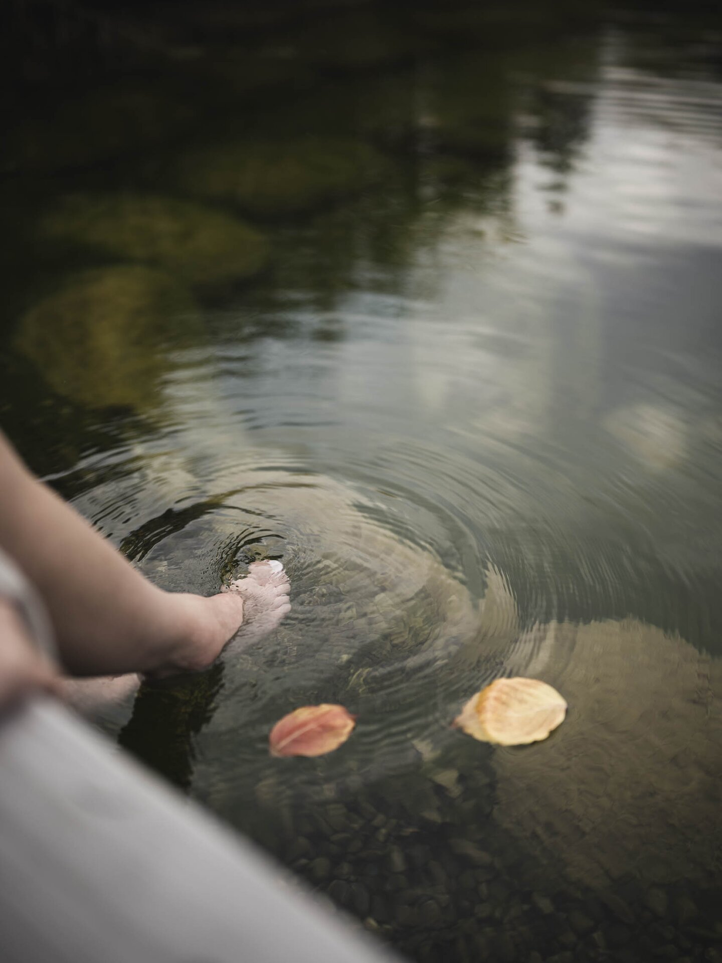 Füße baumeln im Engel Bergsee im Herbst, ein paar Herbstblätter schwimmen an der Oberfläche