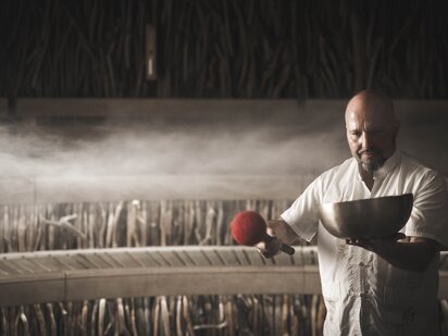 Jens (Saunameister) mit Klangschale in der Hand beim Saunaaufguss in der Event Sauna