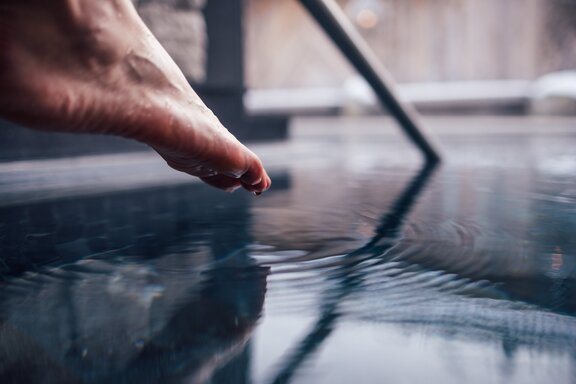 Person tippt mit Zehenspitzen in den Kaltwasserpool im Engel