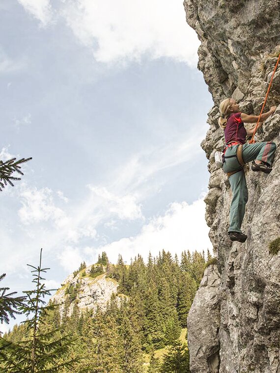 Person beim Klettern in Felswand im Tannheimer Tal Person beim Klettern in Felswand im Tannheimer Tal