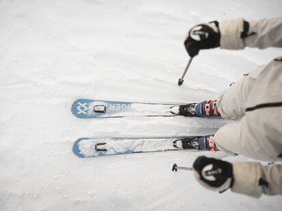 Vogelperspektive auf Skifahrer mit blauen Völkel Ski und beigem Scott Skianzug - Skiurlaub im Tannheimer Tal