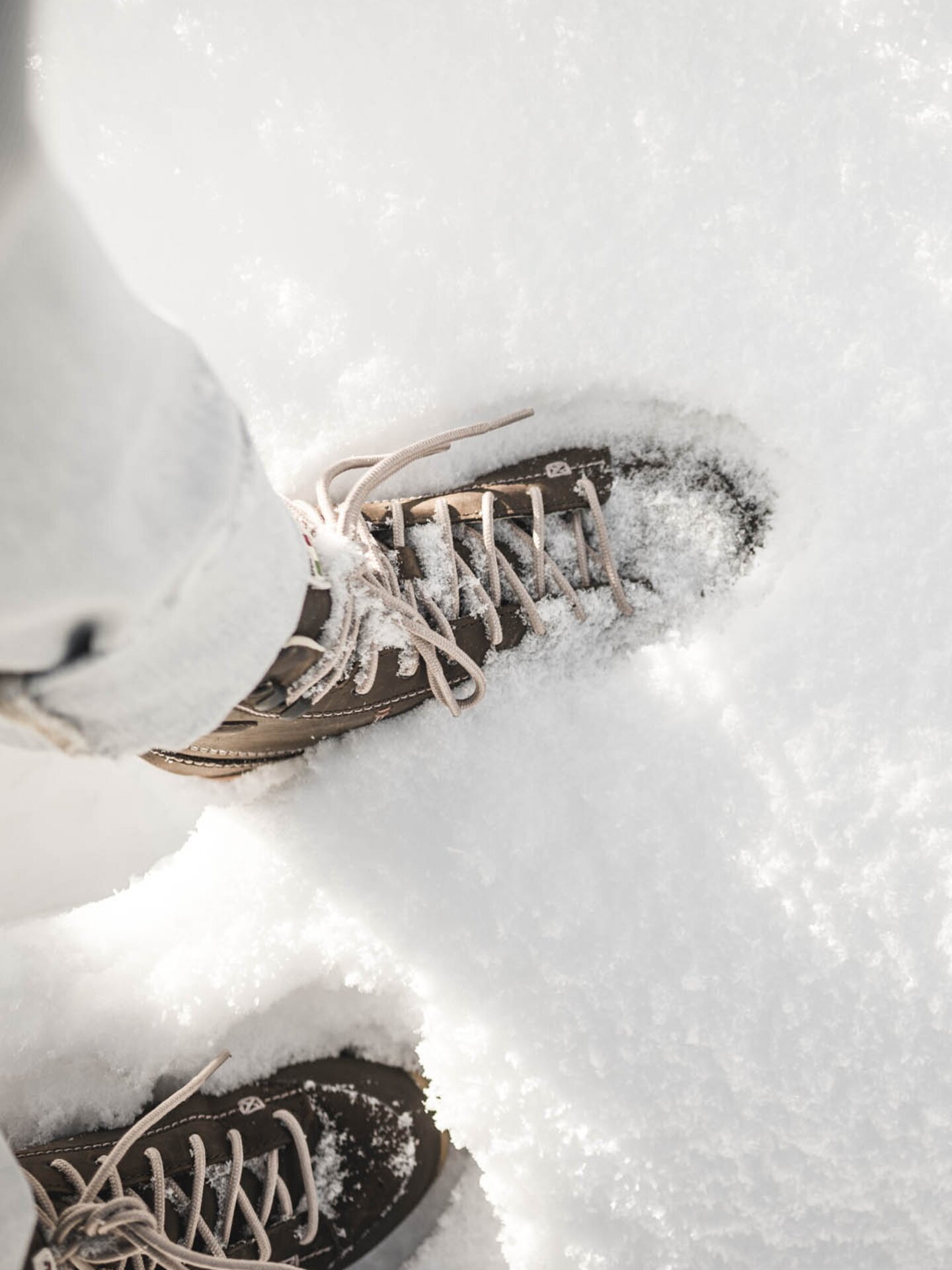 Person stapft mit braunen Winterschuhen im Neuschnee