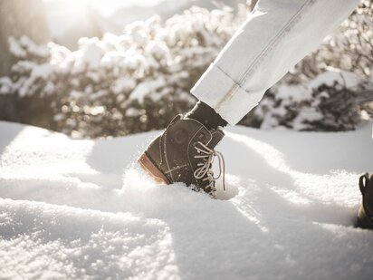 Person mit Winterschuhen stapft im frischen Pulverschnee im Tannheimer Tal 