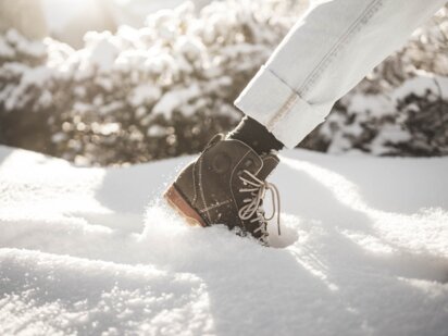 Person mit Winterschuhen stapft im frischen Pulverschnee im Tannheimer Tal 