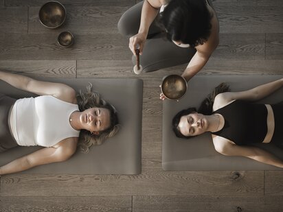Zwei Personen liegend auf einer Gymnastikmatte bei einer Klangmeditation im Wellnesshotel Der Engel