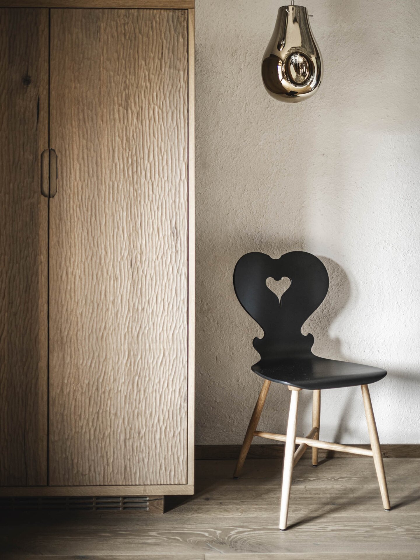 Designerstuhl neben Schrank-Bar unter Designerleuchte | Hoteldesign