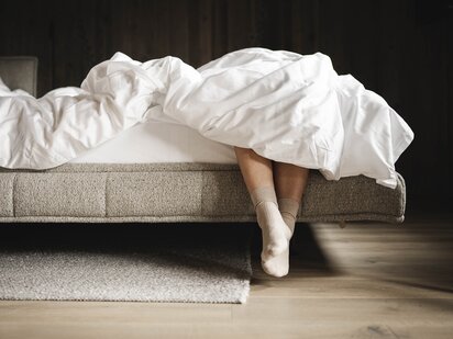 Person lässt Beine vom Bett raus hängen im Orgänic Top Komfortzimmer Nord
