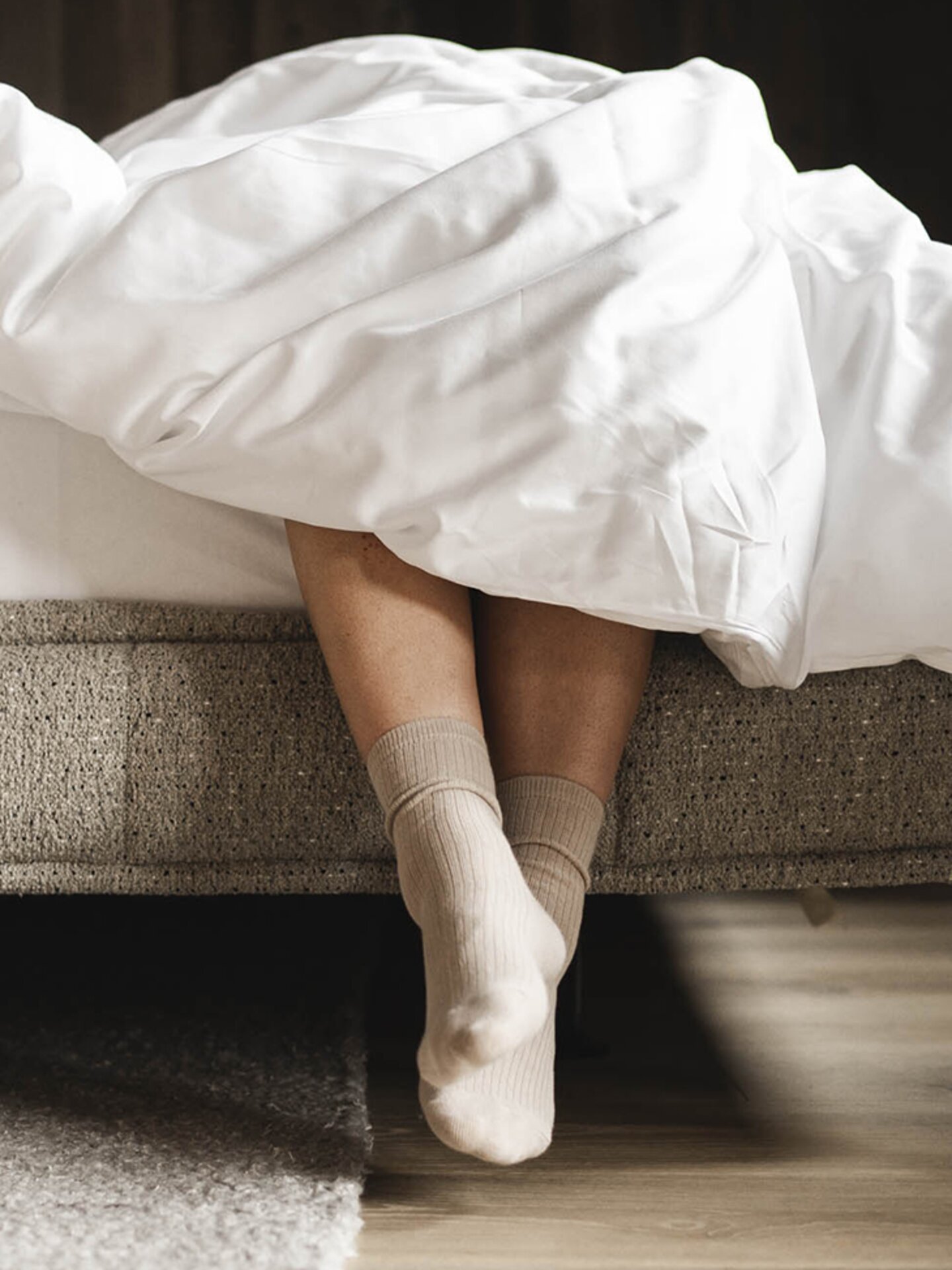 Person lässt Beine vom Bett raus hängen im Orgänic Top Komfortzimmer Nord