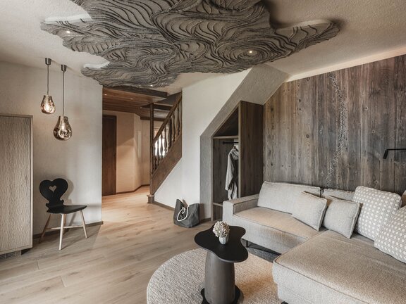 Orgänic Deluxe Suite "Häven" | Blick auf das Wohnzimmer mit Designercouch, Designlampe altem Stuhl