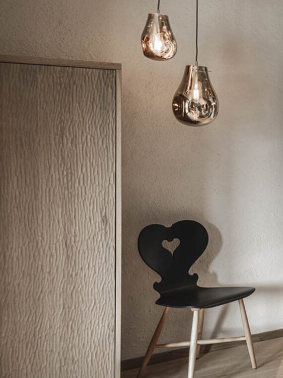 Orgänic Deluxe Suite "Häven" | Blick auf das Wohnzimmer mit Designercouch, Designlampe altem Stuhl Orgänic Deluxe Suite "Häven" | Blick auf das Wohnzimmer mit Designercouch, Designlampe altem Stuhl