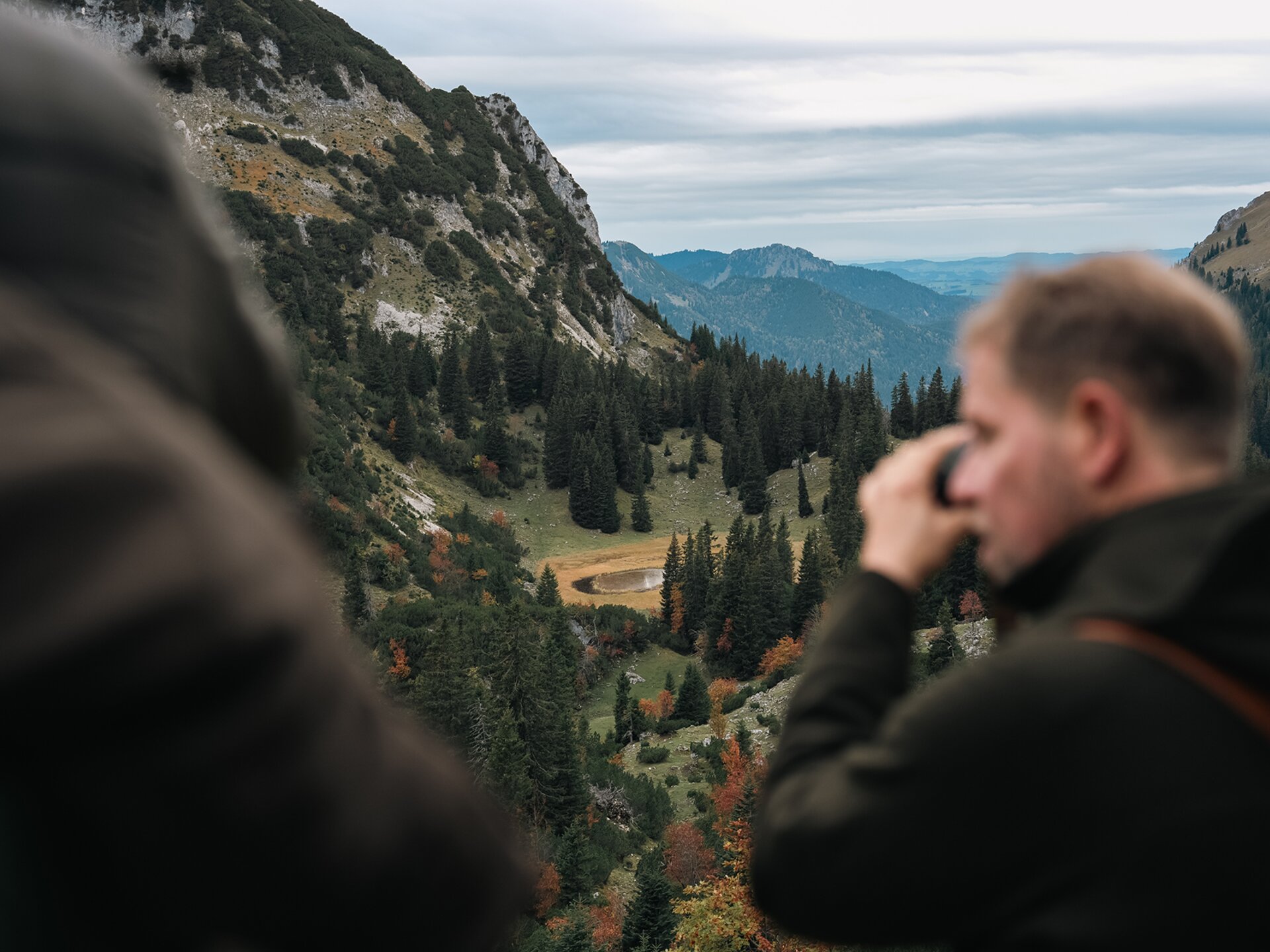 Jäger beobachtet mit einem Fernglas die herbstliche Berglandschaft im Tannheimer Tal