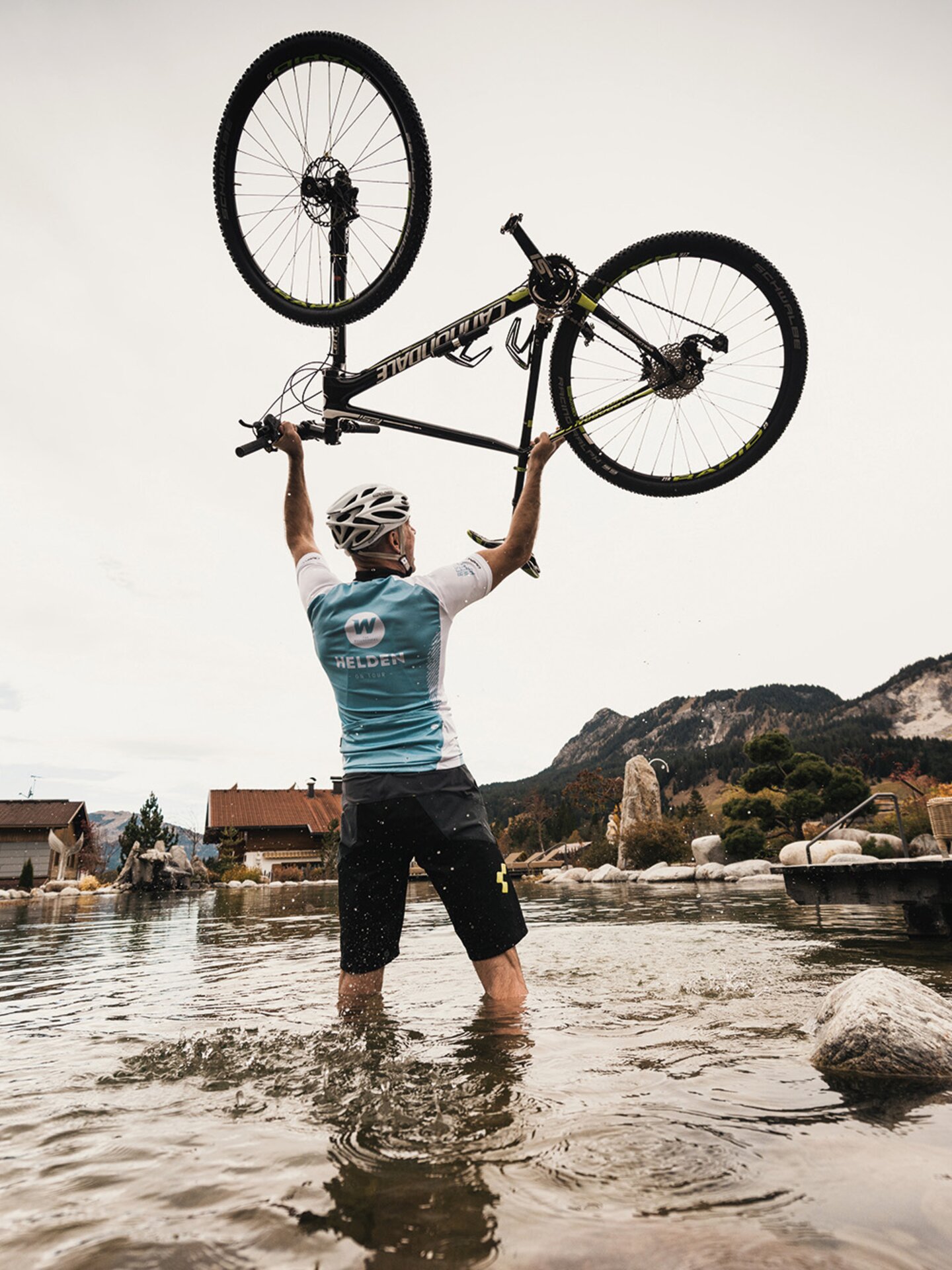 Mountainbiker in Bergsee hebt Rad über den Kopf | Der Engel in Tirol